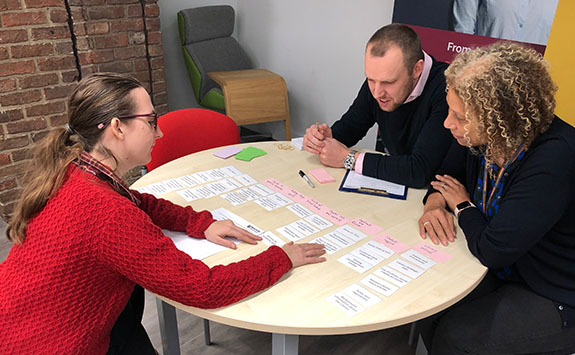 Staff and students looking at cards on a table